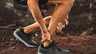 Läufer hat Hand an Achillessehne.
