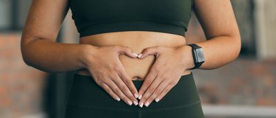 Frau in Sportkleidung legt die Hände auf den Bauch