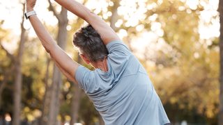 Frau stretcht ihren Rücken im Park.