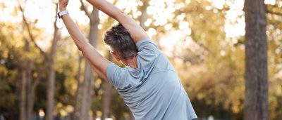 Frau stretcht ihren Rücken im Park.