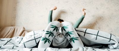 Frau mit Socken mit Cannbismotiv liegt im Bett.