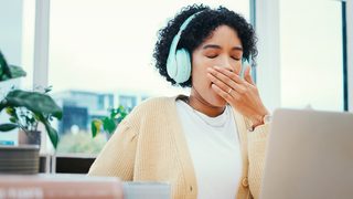 Frau sitzt am Laptop und langweilt sich bei der Arbeit.