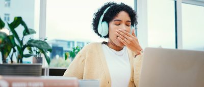 Frau sitzt am Laptop und langweilt sich bei der Arbeit.