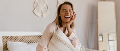 Frau sitzt auf einem Bett und lacht.