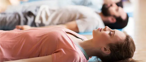 Frau meditiert auf der Yogamatte zur Entspannung bei Magenbeschwerden.