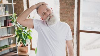 Älterer Mann stretcht seinen verspannten Nacken.