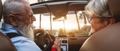 Älteres Pärchen fährt mit dem Auto in den Urlaub.