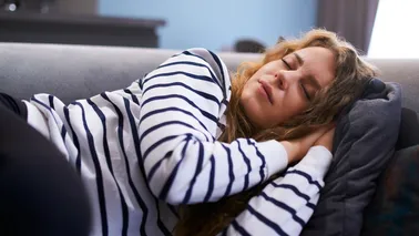 Frau macht Powernapping auf der Couch.