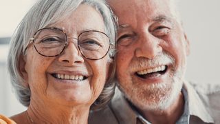 Älterer Mann und ältere Frau lachen in die Kamera.