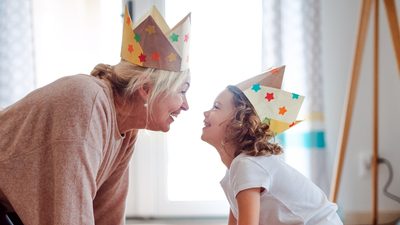 Lächelnde Großmutter und Enkelin mit selbstgebastelten Kronen.