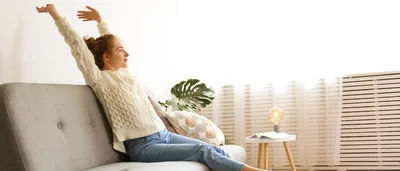 Frau entspannt kurz auf grauem Sofa.