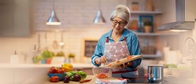 Frau kocht mit frischen Zutaten in der Küche – bekömmliche Ernährung bei Magenentzündung