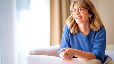 Eine fröhliche Frau mittleren Alters sitzt auf einem Sessel