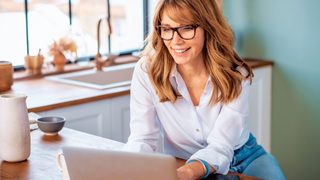 Frau im Homeoffice nutzt Laptop und legt das Smartphone beiseite – sie begegnet digitalem Stress bewusst.