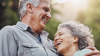 Ein Paar über 60 Jahre lacht zufrieden und umarmt sich