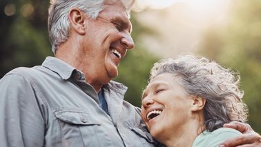 Ein Paar über 60 Jahre lacht zufrieden und umarmt sich