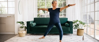 Ältere Frau in ihrem Wohnzimmer beim Gleichgewichtstraining