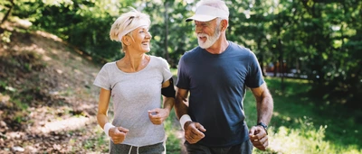 Ältere Frau und Mann beim Joggen durch den Wald