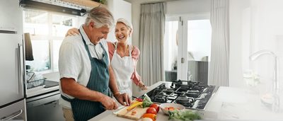 Älteres Paar lacht gemeinsam beim Kochen – Wohlbefinden ohne Sodbrennen