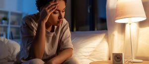 Frau sitzt im Bett und kann nicht schlafen