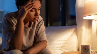 Frau sitzt im Bett und kann nicht schlafen