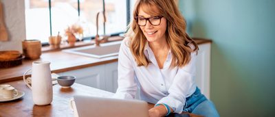 Eine Frau arbeitet am Laptop in gemütlicher Umgebung – Tipps gegen Schwindel bei Bildschirmarbeit