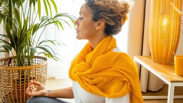 Eine Frau meditiert im Wohnzimmer und findet mentale Entspannung
