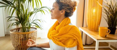 Eine Frau meditiert im Wohnzimmer und findet mentale Entspannung