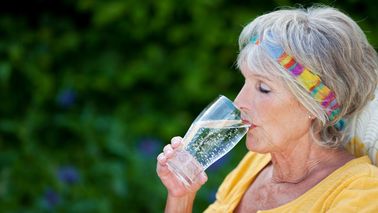 Ältere Frau trinkt ein großes Glas Wasser