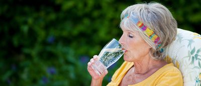 Ältere Frau trinkt ein großes Glas Wasser