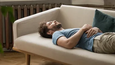 Mann macht eine Entspannungsübung auf dem Sofa. 