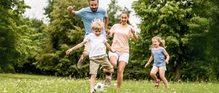 Familie mit zwei kleinen Kindern spielen fröhlich Fußball – gemeinsamer Sommertag in der Natur