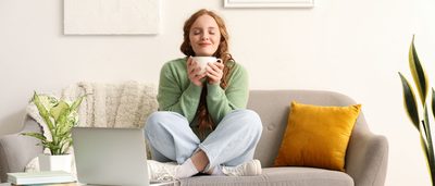 Entspannte Frau mit einer Tasse Tee auf dem Sofa – Stressabbau kann helfen, Blasenentzündungen durch Stress zu vermeiden.