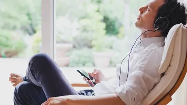 Mann hört über Kopfhörer entspannende Klaviermusik