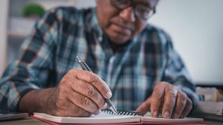 Mann schreibt in ein Schwindel-Tagebuch.