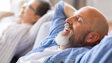 Ältere Mann und Frau entspannen zuhause auf der Couch.