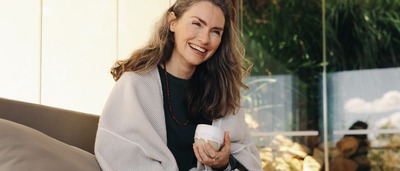 Ältere fröhliche Frau sitzt mit Tasse auf Terrasse