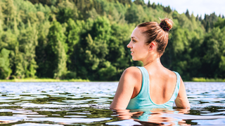 Frau entspannt sich beim Schwimmen im See um Stress abzubauen.
