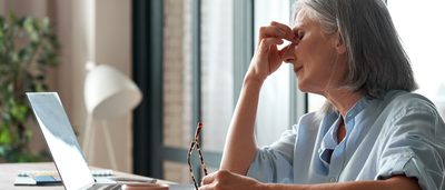 Ältere erschöpfte Frau am Laptop
