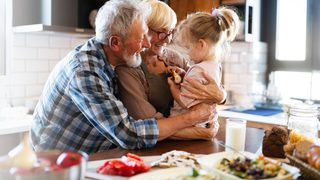 Älteres Paar mit Enkelkind in der Küche – gesunde Ernährung für die Funktion des Verdauungssystems