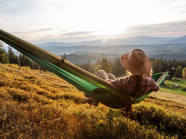 Mann sitzt in einer Hängematte und schaut in die Ferne