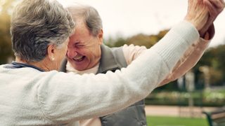 Älterer Mann und ältere Frau tanzen in der Natur.