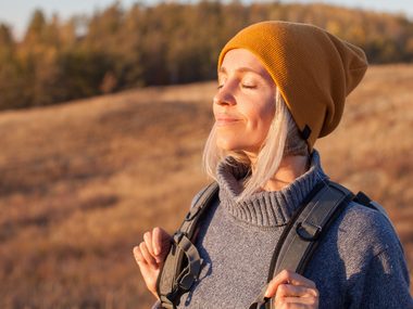 Frau atmet in der Natur durch - frische Luft hilft bei Kopf- und Nervenschmerzen