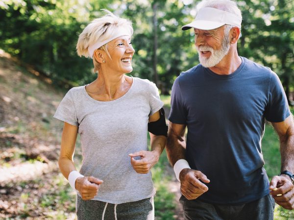 Älteres Paar joggt fröhlich in der Natur. Regelmäßige Bewegung fördert die Herzgesundheit und stärkt das Kreislaufsystem.