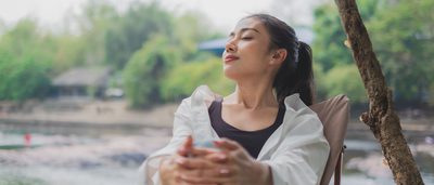 Frau sitzt entspannt auf einem Stuhl und genießt die Natur.
