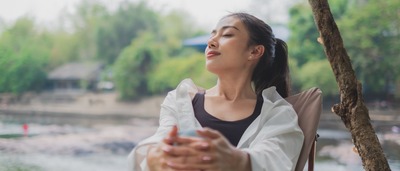 Frau sitzt entspannt auf einem Stuhl und genießt die Natur.