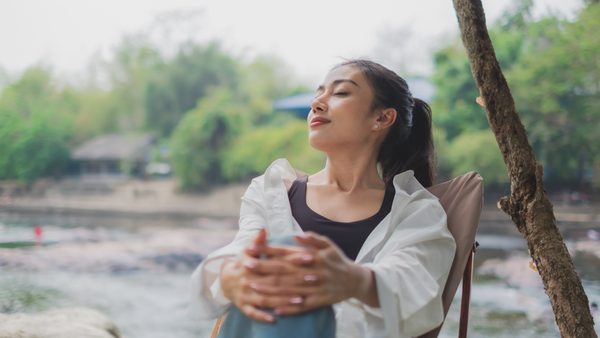 Asiatische Frau mit geschlossenen Augen ruht sich kurz im Sitzen aus .