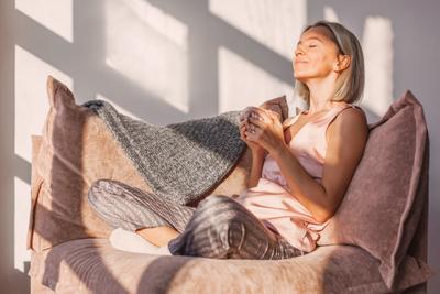 Frau entspannt mit einer Tasse Tee auf einer Couch.