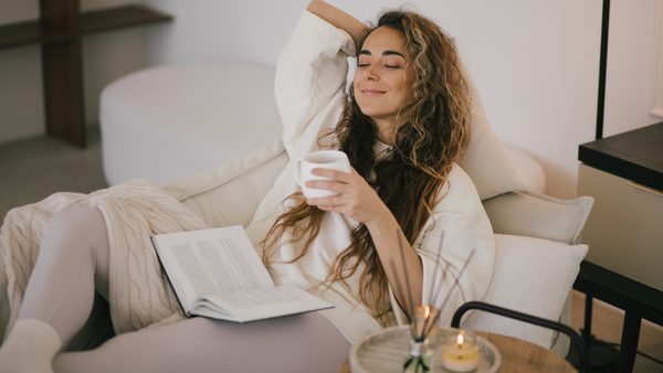 Frau sitzt auf dem Sofa und trinkt Tee bei Nasennebenhöhlenentzündung.