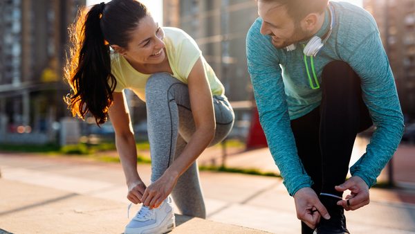 Mann und Frau binden sich die Sportschuhe für einen Lauf in der Stadt